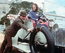 Diana Rigg as Mrs. Emma Peel on the British spy series, The Avengers. She is shown at the wheel of a car which is being pushed by co-star Patrick MacNee (John Steed).